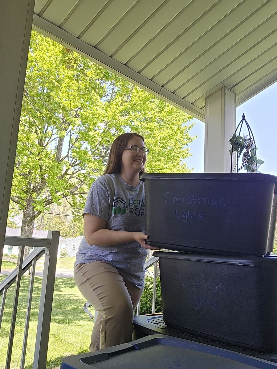 Stephanie lifting a holiday decoration bin on a customer porch